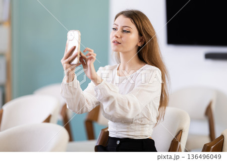 Young female student taking photo on smartphone at training 136496049