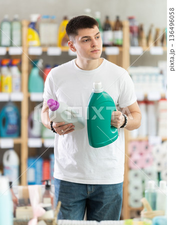 Young man buyer chooses detergent in store 136496058