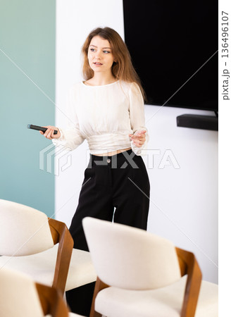 Girl teacher speaker with remote control during lecture Girl teacher speaker with remote control during lecture 136496107