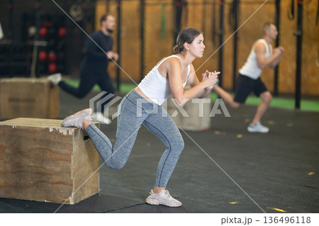 Sportive young girl practicing one leg squats with box during crossfit workout 136496118
