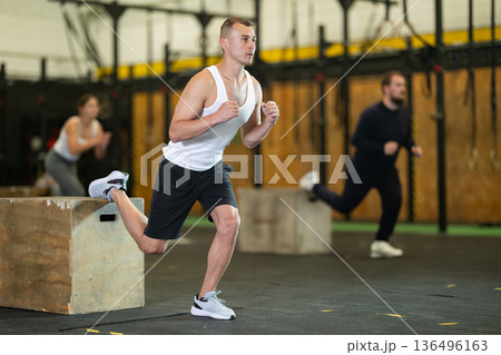 Sportive young guy practicing one leg squats with box during crossfit workout Sportive young guy practicing one leg squats with box during crossfit workout 136496163