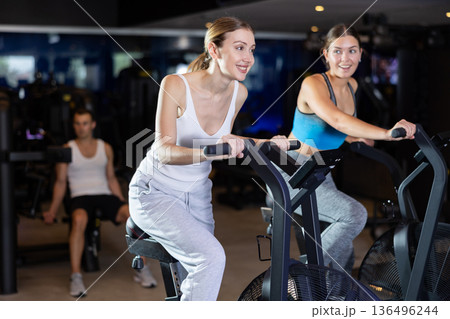 Sportive young girls doing air bike exercises in well-equipped gym 136496244
