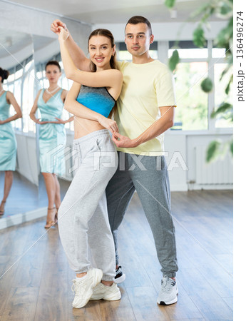 Couple in comfortable sports clothes waltz dancing during individual lesson Couple in comfortable sports clothes waltz dancing during individual lesson 136496274
