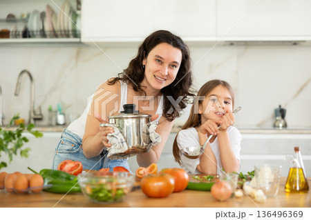 Mom and little daughter are standing at kitchen table with dishes in their hands. Mom and little daughter are standing at kitchen table with dishes in their hands. 136496369