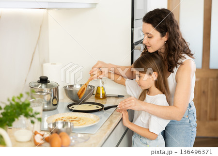 Mom and her daughter fry pancakes 136496371