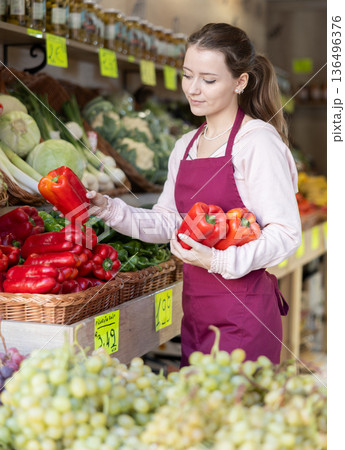 Woman seller laying out red bell pepper Woman seller laying out red bell pepper 136496376