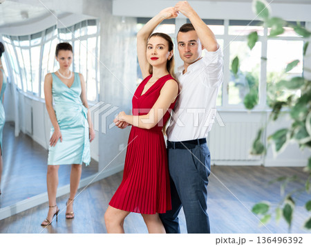 Man practicing samba with female partner in red in dance class Man practicing samba with female partner in red in dance class 136496392