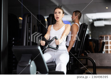 Sportive young girl training her arms using cable exercise machine in gym Sportive young girl training her arms using cable exercise machine in gym 136496395