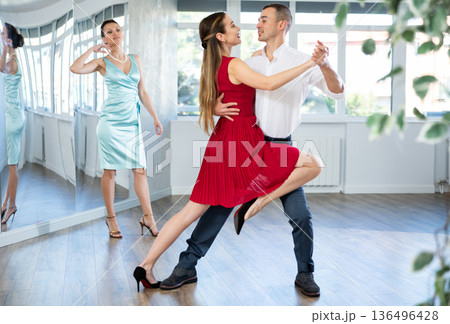 Couple in stage costumes learns tango dancing during individual lesson Couple in stage costumes learns tango dancing during individual lesson 136496428