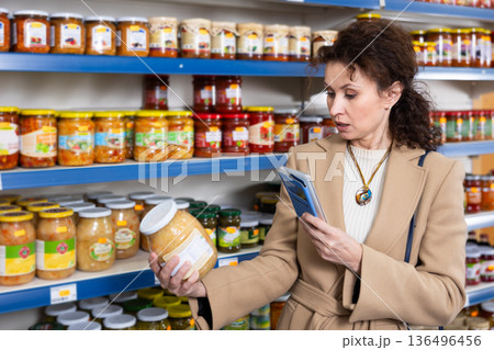 Female shopper scans barcode on jar of sauerkraut using a smartphone while shopping in grocery store Female shopper scans barcode on jar of sauerkraut using a smartphone while shopping in grocery store 136496456