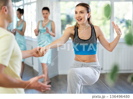 Cheerful woman practicing vigorous swing with man at dance class Cheerful woman practicing vigorous swing with man at dance class 136496480