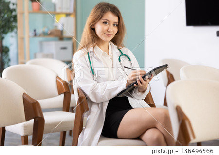 During lecture, young woman medical listener makes notes on tablet 136496566