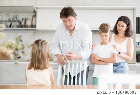 At home in kitchen, parents scold their daughter for careless act 136496608