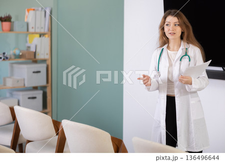 Girl doctor speaker with paper data report during lecture 136496644