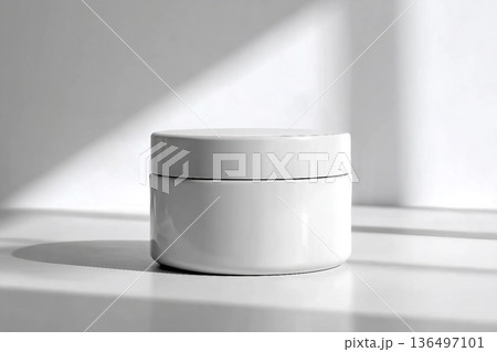 Blank white cream jar on a white background with soft, natural light and shadows. An elegant and minimalist mockup for beauty or skincare products. 136497101