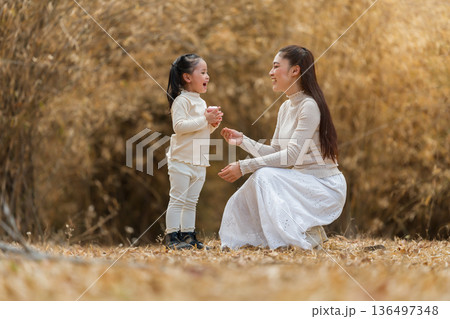 Mother teaching child girl how to use pink toy camera in the park or dry bamboo forest Mother teaching child girl how to use pink toy camera in the park or dry bamboo forest 136497348