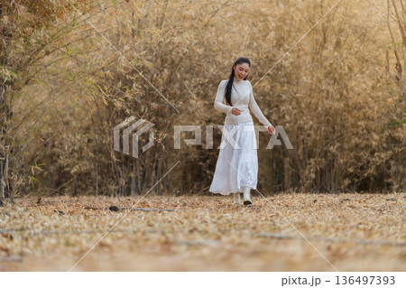woman walking through a dry forest, golden woodland woman walking through a dry forest, golden woodland 136497393