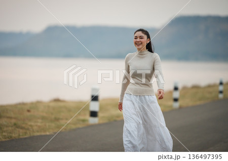 woman walking on a scenic road during dusk near the river. woman walking on a scenic road during dusk near the river. 136497395