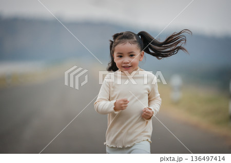 Energetic little child girl running happily on an open road by the water Energetic little child girl running happily on an open road by the water 136497414