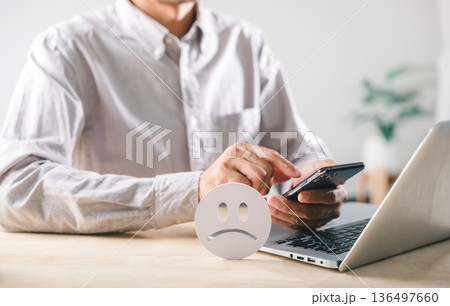Negative customer feedback signals low satisfaction, bad review posted online using mobile phone and laptop, person expresses unhappy experience, showing overall poor rating or complaint Negative customer feedback signals low satisfaction, bad review posted online using mobile phone and laptop, person expresses unhappy experience, showing overall poor rating or complaint 136497660