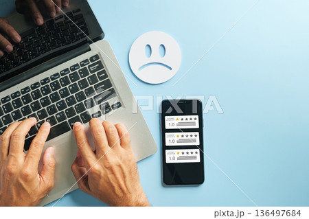 Customer satisfaction phone survey review shows poor service feedback on mobile laptop computer screen, depicting negative online experience with sad face icon 136497684