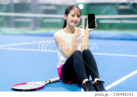 テニスコートでスマホを持つ女性 テニスコートでスマホを持つ女性 136498141