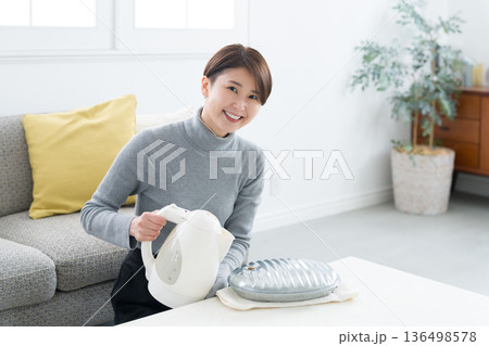 湯たんぽにお湯を入れる冷え性の女性 136498578