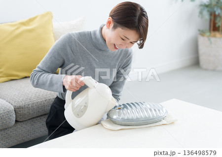 湯たんぽにお湯を入れる冷え性の女性 136498579