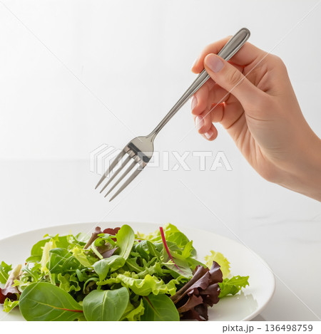 フォークを持ちサラダを食べる手のクローズアップ フォークを持ちサラダを食べる手のクローズアップ 136498759