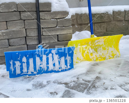Snow shovels are standing outside 136501228
