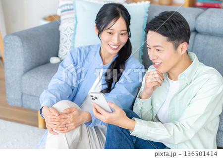 リビングでスマホを見るカップル リビングでスマホを見るカップル 136501414