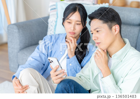 リビングでスマホを見るカップル リビングでスマホを見るカップル 136501483