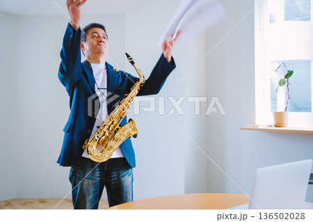 自宅でサックスの練習をするシニア男性 136502028