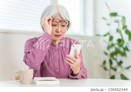 老眼でスマホの文字がよく見えないシニア女性（スマホ老眼,老眼鏡,ピント,眼精疲労） 136502344