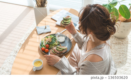 リビングテーブルで食事をするおしゃれな若いアジア人女性 136503620