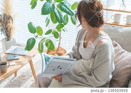 リビングのソファーに座り雑誌を読むオシャレなアジア人女性 リビングのソファーに座り雑誌を読むオシャレなアジア人女性 136503958