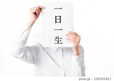 一日一生と書かれた紙を持つ白いシャツを着た人物 136505921