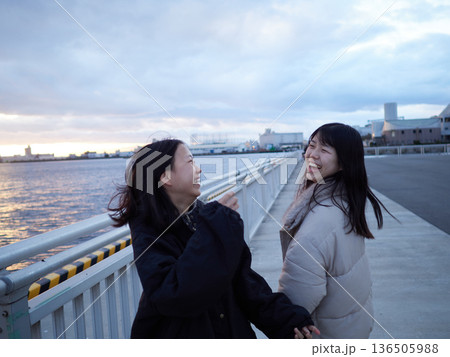 冬休みの夕方の名古屋港の堤防で遊んでいる中学生姉妹の姿 冬休みの夕方の名古屋港の堤防で遊んでいる中学生姉妹の姿 136505988