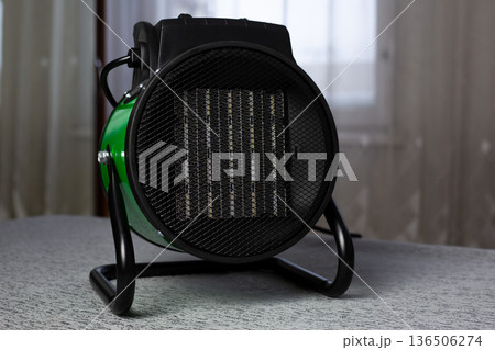 Industrial heater with round mesh design, showcasing sturdy base and heating elements. Ideal for home, workshops or garages, providing warmth in cold environment Industrial heater with round mesh design, showcasing sturdy base and heating elements. Ideal for home, workshops or garages, providing warmth in cold environment 136506274