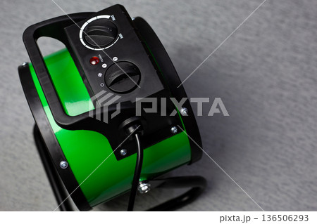 Top view of the control panel of space heater. Concept of increasing temperature with compact heater. Warming in cold weather. Home appliance with controls. Gun heater in green color Top view of the control panel of space heater. Concept of increasing temperature with compact heater. Warming in cold weather. Home appliance with controls. Gun heater in green color 136506293