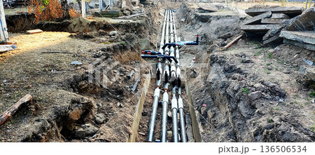 Underground utility pipes installation in trench construction site; infrastructure development project with excavated earth and concrete debris present Underground utility pipes installation in trench construction site; infrastructure development project with excavated earth and concrete debris present 136506534
