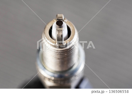 Close up view of spark plug electrode and ceramic insulator against blurred background automotive engine ignition component for internal combustion 136506558