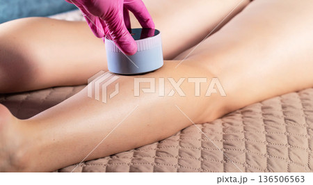 The hand of a cosmetologist makes an anti-cellulite massage with a portable vacuum massager, close-up, effective 136506563