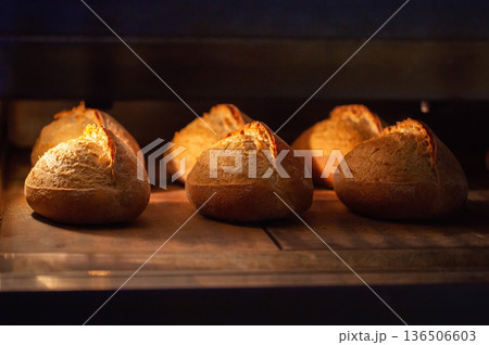 Freshly baked bread loaves with golden brown crust warm from oven, highlighting manual production bakery products at large scale factory 136506603