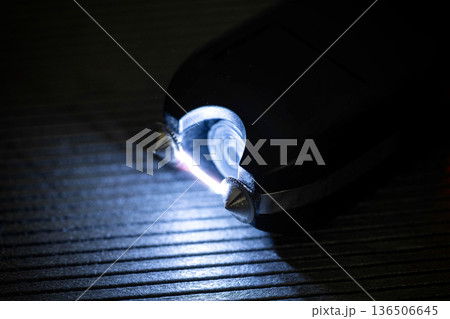 Close up view of electroshocker creating electric arc between metal prongs demonstrating danger and power of self defense device in dark environment. 136506645
