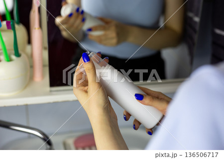 Girl hands holding closed bottle of cleansing foam. White bottle with lid of facial skincare. Products for body and skin care. Concept for women who care about their bodies and skin 136506717