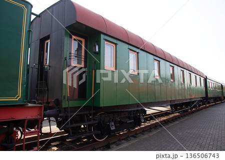 Historic green and red train carriage displayed in a railway museum during a sunny day Historic green and red train carriage displayed in a railway museum during a sunny day 136506743