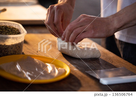 Hands of person shaping dough on wooden surface for baking preparation cooking food close-up homemade kitchen activity culinary process ingredient wholesome organic 136506764