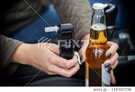 Closeup Of Hands With Beer Bottle And Alcohol Tester. Making A Choice About Driving Under Influence. Closeup Of Hands With Beer Bottle And Alcohol Tester. Making A Choice About Driving Under Influence. 136507296