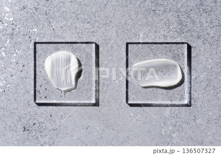A sample of white body cosmetics on a glass square. Grey background. A sample of white body cosmetics on a glass square. Grey background. 136507327